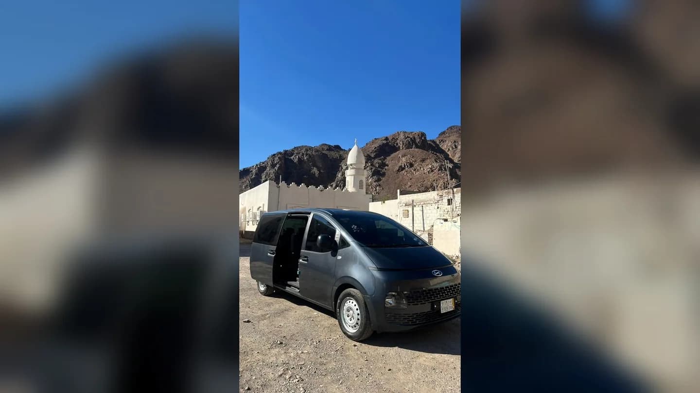 Taxi Bhai Hyundai Staria 7-seater van at a Makkah mosque with mountains — private Umrah transfer